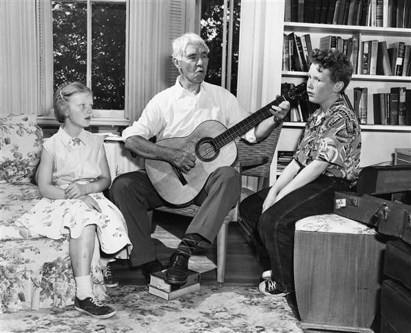 Carl Sandburg playing the guitar and singing with his grandchildren, Paula & John